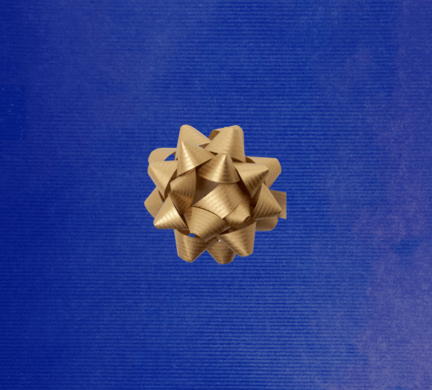 image of a square of wrapping paper, the paper is a solid dark blue kraft paper, in the corner of the gift wrap paper is a gold gift wrapping bow
