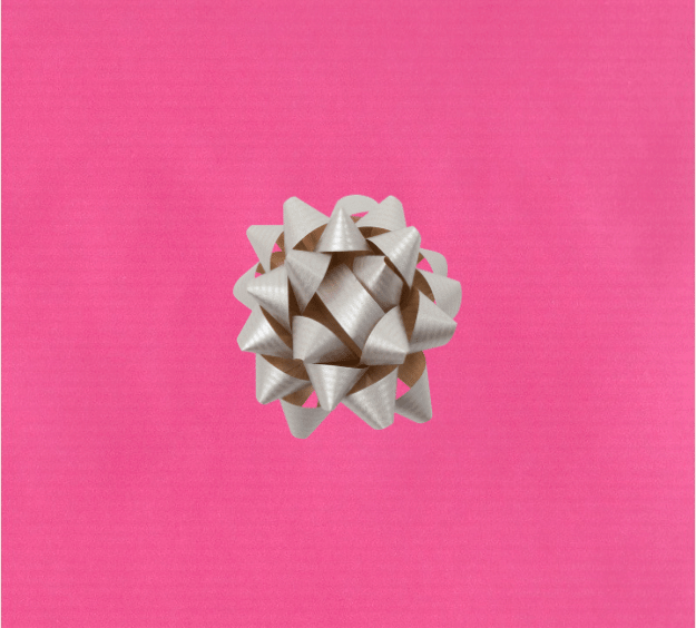 image of a square of pink wrapping paper, the paper is a solid fuchsia kraft paper, in the corner of the gift wrap paper is a silver gift wrapping bow