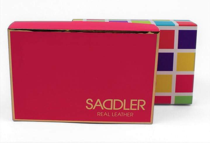 Image of a saddler leather purse gift box. The box is red with gold trim and has saddler branded tissue paper in it with a purse inside.