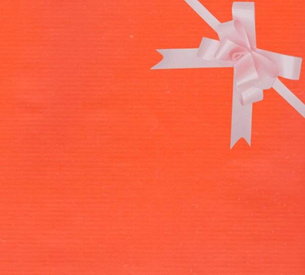 image of a square of wrapping paper, the paper is a solid orange kraft paper, in the corner of the gift wrap paper is a light pink gift wrapping bow