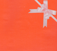 image of a square of wrapping paper, the paper is a solid orange kraft paper, in the corner of the gift wrap paper is a light pink gift wrapping bow