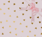 image of a square of wrapping paper, the paper has a pink background and features lots of little gold hearts all over it, in the centre of the gift wrap paper is a gold paper gift wrapping bow