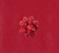 image of a square of wrapping paper, the paper is a solid dark red kraft paper, in the corner of the gift wrap paper is a red gift wrapping bow