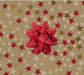 image of a square of wrapping paper, the paper has a gold background and features lots of red, gold and cream stars , in the corner of the gift wrap paper is a red gift wrapping bow