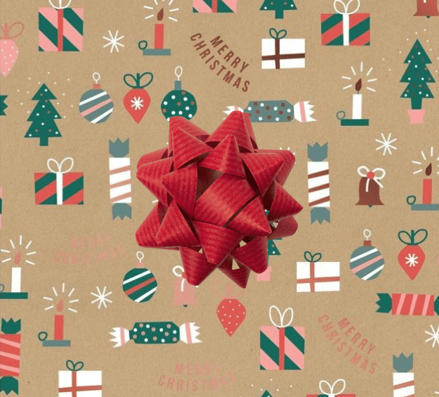 image of a square of wrapping paper, the paper has a gold background with the words merry christmas on it and lots of colouful illustrations of traditional christmas items such as presents, crackers and tree decorations., in the corner of the gift wrap paper is a gold gift wrapping bow