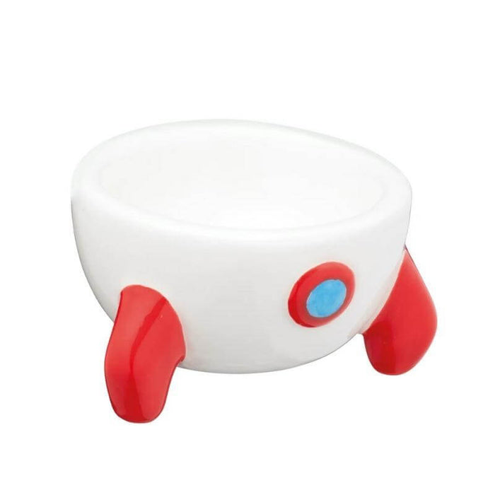 image of a rocket egg cup. its a white egg cup with red rocket legs and a red and blue circular rocket decoration