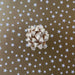 image of a square of wrapping paper, the paper is gold and features lots of solid white stars, in the corner of the gift wrap paper is a red gift wrapping bow