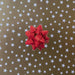 image of a square of wrapping paper, the paper is gold and features lots of solid white stars, in the centre of the gift wrap paper is a silver paper gift wrapping bow