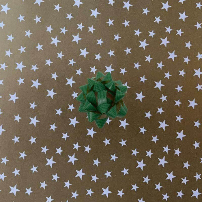 image of a square of wrapping paper, the paper is gold and features lots of solid white stars, in the corner of the gift wrap paper is a white gift wrapping bow